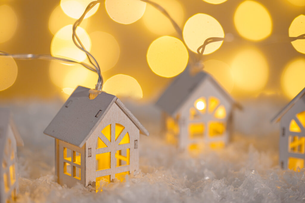 Small wooden structures with christmas lights and covered porches in the snow.