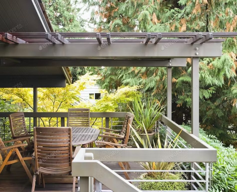 A covered deck on the outside of a wooden house with wooden deck chairs